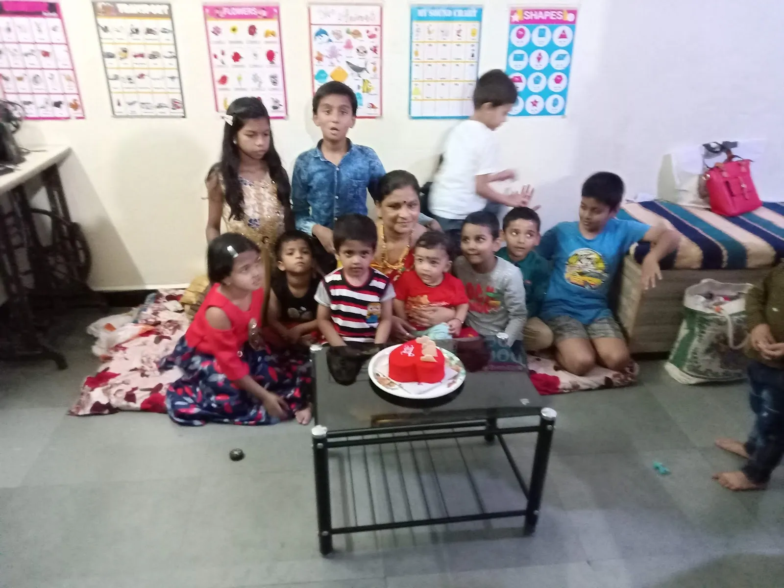 Children and caretaker gathered around a birthday cake at Maza Ghar Day Care